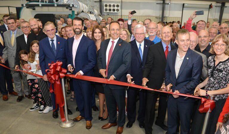 group of people cutting a ribbon inside factory
