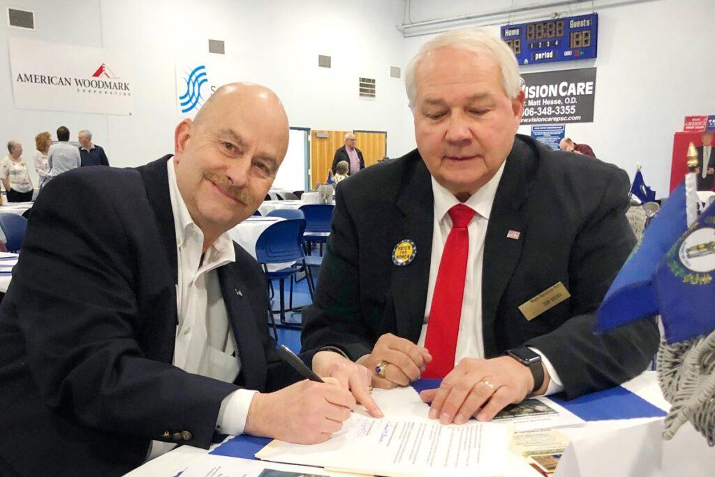 two men signing paperwork