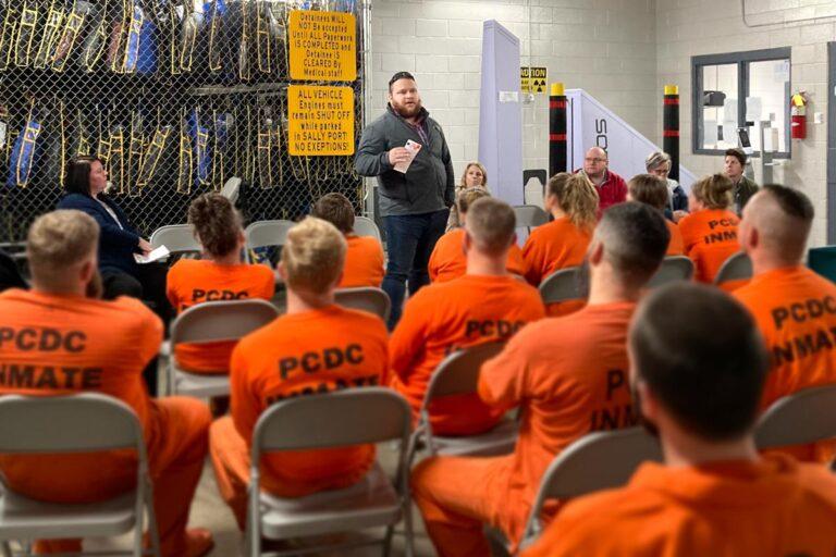 man speaking to group of inmates in a classroom setting