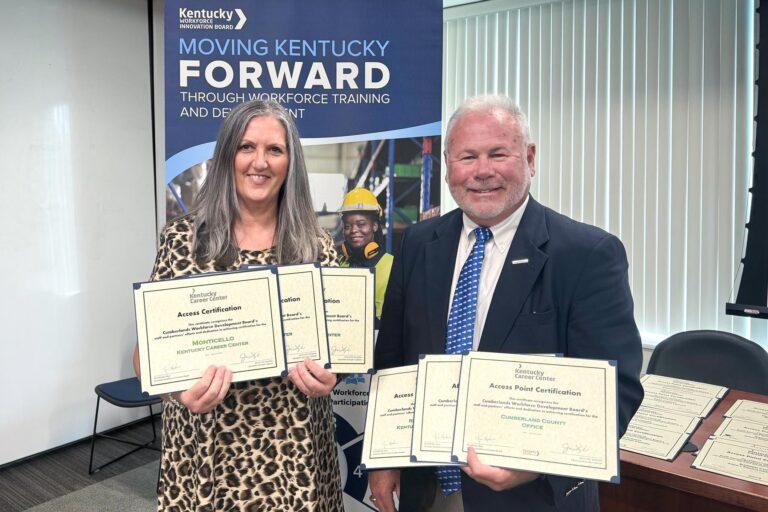 two people holding awards certificates